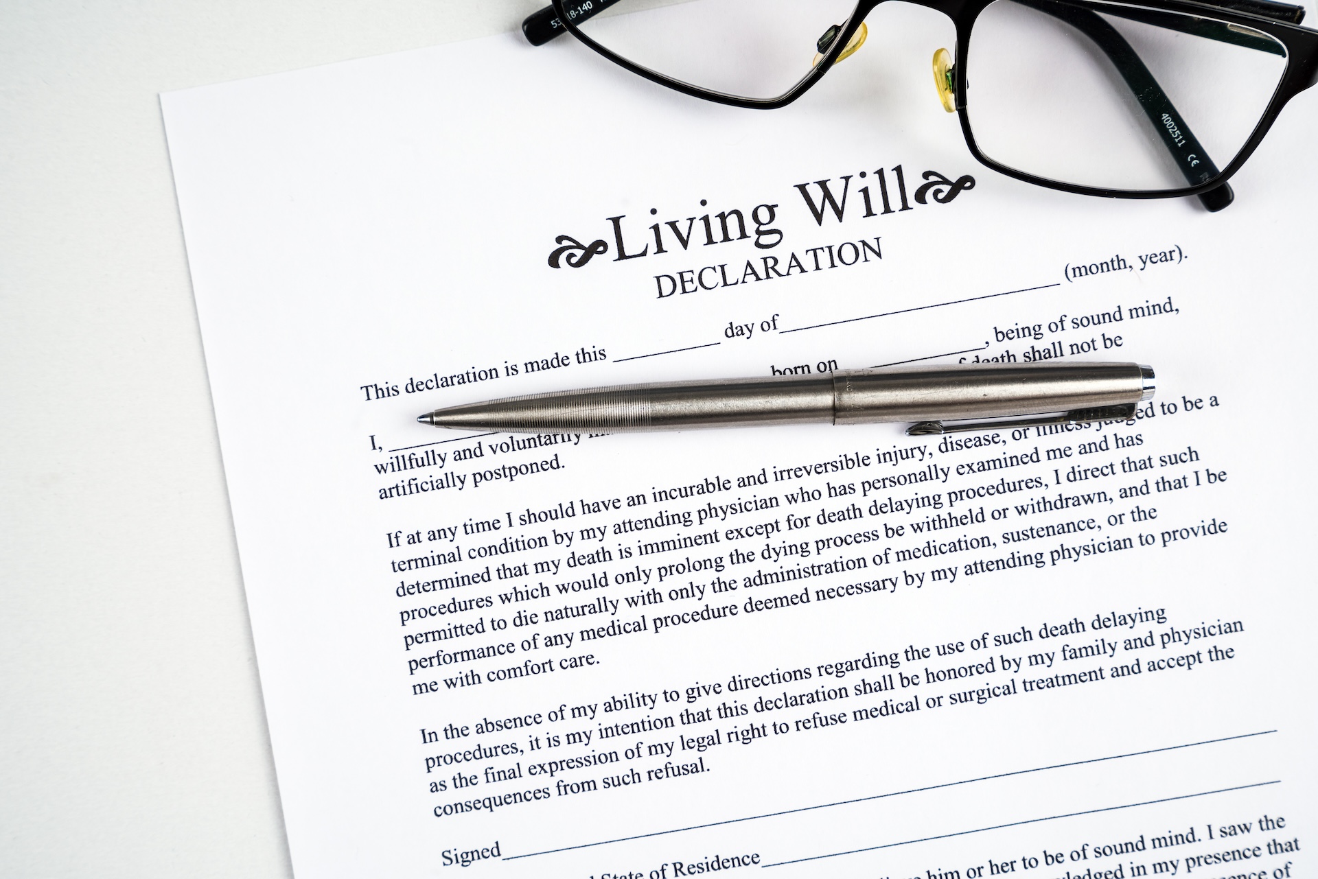 Living will declaration form with glasses and silver pen.